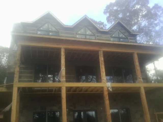 Dormers and porch framing on a large log home under construction — Roof Coating work by our crew in Covington